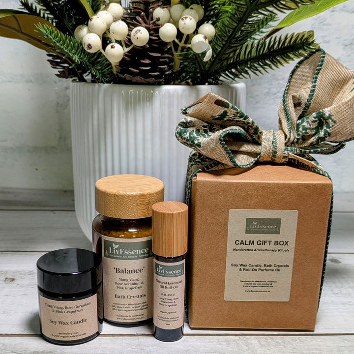 Calm gift box with essential oil bottles and candles on a wooden surface.
